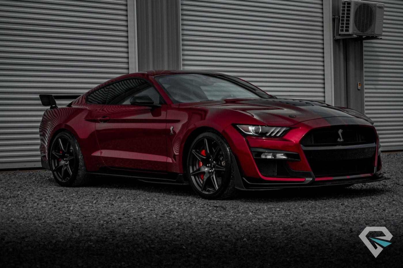 Crimson Shelby GT500 front three-quarter in moody shop light