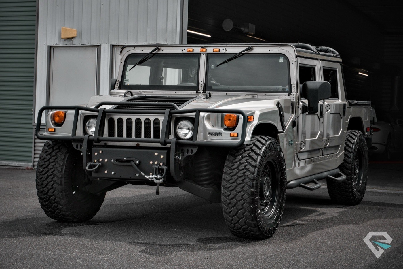 Silver Hummer H1 head-on in front of the shop doors