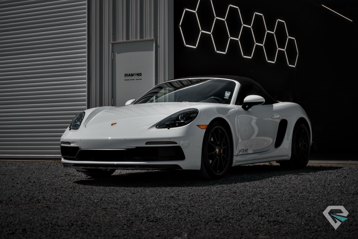 White Porsche Boxster beside a lit hexagon wall